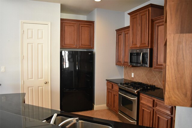 3123 Dallas St, Houston, TX 77003 - kitchen featuring stainless steel appliances, dark countertops, decorative backsplash, and brown cabinets