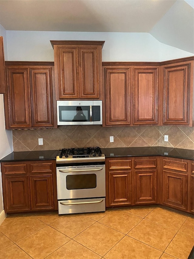 3123 Dallas St, Houston, TX 77003 - kitchen featuring appliances with stainless steel finishes, dark countertops, light tile patterned flooring, backsplash, and vaulted ceiling