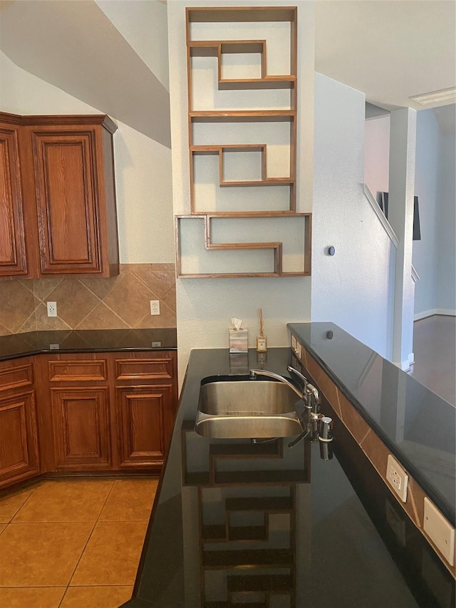 3123 Dallas St, Houston, TX 77003 - kitchen featuring a sink, brown cabinets, tasteful backsplash, dark countertops, and light tile patterned floors