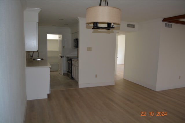 7575 Katy Fwy Unit 9, Houston, TX 77024 - unfurnished living room featuring a sink, light wood-style floors, crown molding, and baseboards