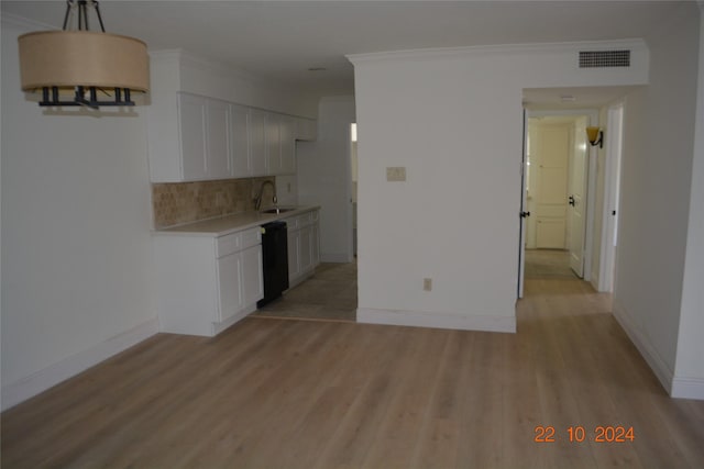 7575 Katy Fwy Unit 9, Houston, TX 77024 - kitchen with black dishwasher, backsplash, light countertops, light wood-type flooring, and white cabinets