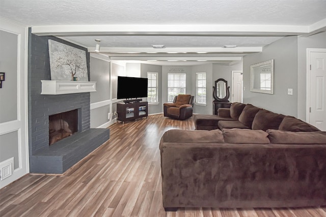 3638 Lost Oak Dr, Spring, TX 77388 - living room with beam ceiling, a brick fireplace, wood finished floors, and a textured ceiling
