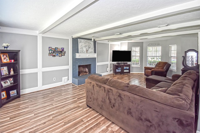 3638 Lost Oak Dr, Spring, TX 77388 - living room with beamed ceiling, a textured ceiling, wood finished floors, a brick fireplace, and baseboards