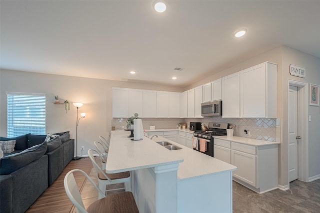 2446 Palisade Crest Dr, Rosharon, TX 77583 - kitchen featuring appliances with stainless steel finishes, a sink, open floor plan, decorative backsplash, and a breakfast bar area