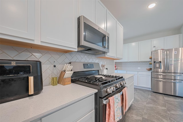 2446 Palisade Crest Dr, Rosharon, TX 77583 - kitchen featuring appliances with stainless steel finishes, white cabinetry, tasteful backsplash, and light stone counters