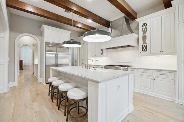 4654 Ingersoll St, Houston, TX 77027 - kitchen with stainless steel built in refrigerator, custom exhaust hood, light wood-type flooring, beamed ceiling, and decorative backsplash