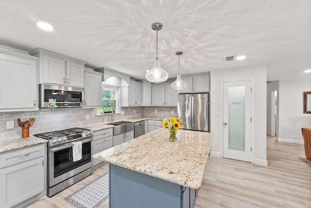 715 Timber Cove Dr, Seabrook, TX 77586 - kitchen with stainless steel appliances, backsplash, a kitchen island, light stone countertops, and light wood-type flooring