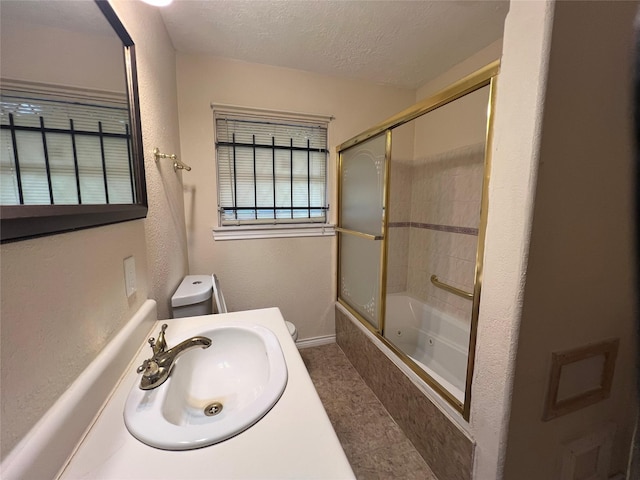 7261 Yoe St, Houston, TX 77016 - full bathroom featuring a sink, toilet, a textured ceiling, combined bath / shower with glass door, and baseboards