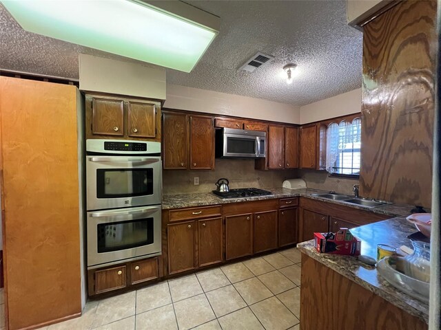 7261 Yoe St, Houston, TX 77016 - kitchen with appliances with stainless steel finishes, a sink, a textured ceiling, and light tile patterned flooring