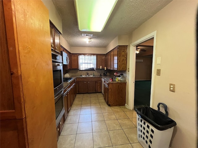 7261 Yoe St, Houston, TX 77016 - kitchen with appliances with stainless steel finishes, a textured ceiling, light tile patterned floors, dark countertops, and a sink