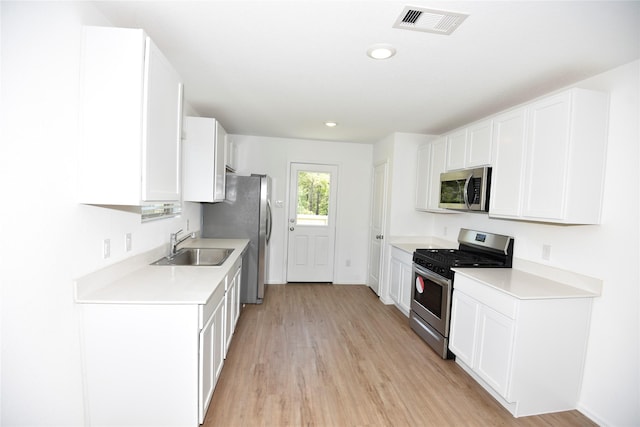 19591 Manduca Dr, New Caney, TX 77357 - kitchen featuring stainless steel appliances, a sink, light wood finished floors, light countertops, and white cabinets