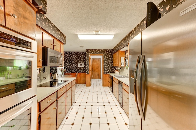 3819 Ridgeview Dr, Missouri City, TX 77459 - kitchen featuring black appliances, wallpapered walls, brown cabinets, light countertops, and a sink