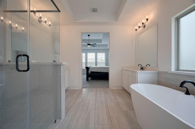 23604 Olive Creek Ln, New Caney, TX 77357 - ensuite bathroom featuring a raised ceiling, a shower stall, a ceiling fan, vanity, and wood tiled floors