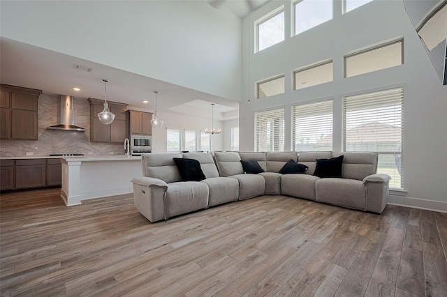 23604 Olive Creek Ln, New Caney, TX 77357 - living room with light wood-type flooring, a high ceiling, a chandelier, and baseboards