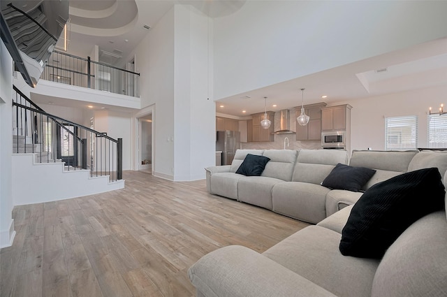 23604 Olive Creek Ln, New Caney, TX 77357 - living room with light wood finished floors, stairs, baseboards, and a towering ceiling