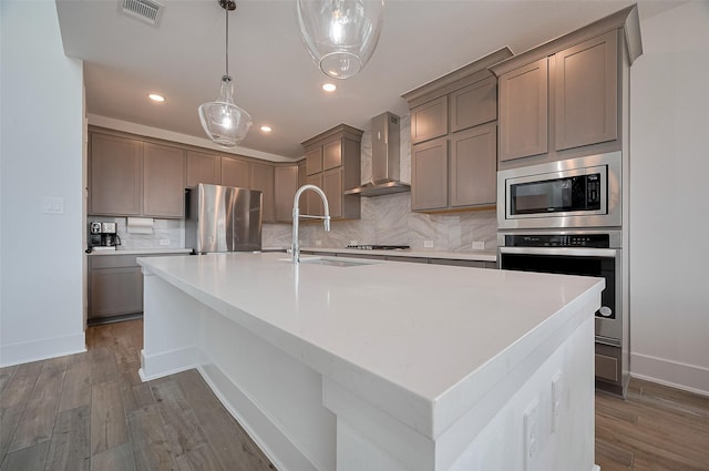 23604 Olive Creek Ln, New Caney, TX 77357 - kitchen featuring wall chimney range hood, appliances with stainless steel finishes, a sink, decorative backsplash, and dark wood-style flooring