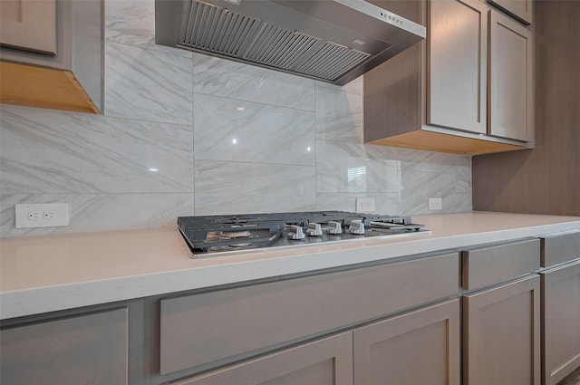23604 Olive Creek Ln, New Caney, TX 77357 - kitchen with wall chimney range hood, stainless steel gas cooktop, tasteful backsplash, and light countertops