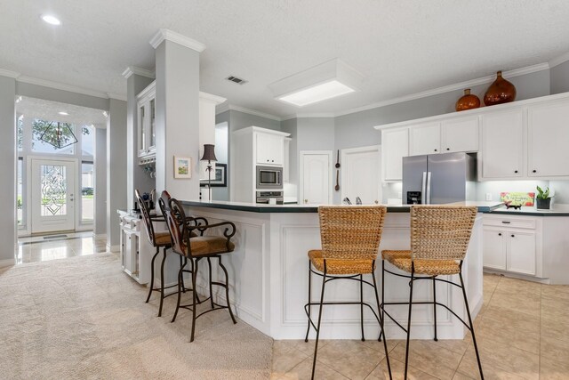 60 Fairfield Dr, Montgomery, TX 77356 - kitchen featuring appliances with stainless steel finishes, a peninsula, crown molding, a breakfast bar area, and white cabinetry