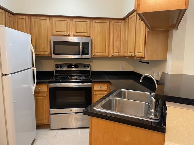 2626 Holly Hall St Unit 409, Houston, TX 77054 - kitchen featuring stainless steel appliances, a sink, dark countertops, light tile patterned floors, and brown cabinetry