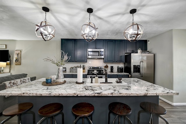 25401 Hunting Trl, Magnolia, TX 77355 - kitchen featuring appliances with stainless steel finishes, a breakfast bar area, baseboards, wood finished floors, and pendant lighting