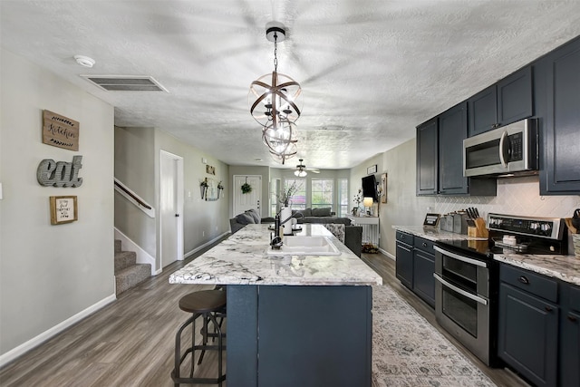 25401 Hunting Trl, Magnolia, TX 77355 - kitchen with stainless steel appliances, a sink, open floor plan, baseboards, and wood finished floors