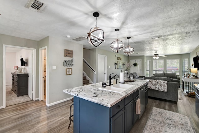 25401 Hunting Trl, Magnolia, TX 77355 - kitchen with a sink, wood finished floors, a textured ceiling, stainless steel dishwasher, and a kitchen bar