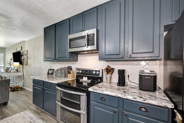 25401 Hunting Trl, Magnolia, TX 77355 - kitchen featuring stainless steel appliances, light wood finished floors, a textured ceiling, baseboards, and tasteful backsplash