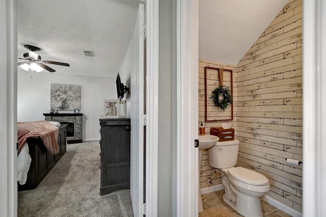 25401 Hunting Trl, Magnolia, TX 77355 - half bathroom featuring lofted ceiling, wood walls, ceiling fan, toilet, and a stone fireplace