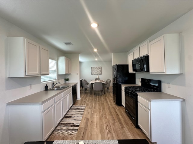 11079 N Lake Mist Ln, Willis, TX 77318 - kitchen featuring black appliances, a sink, white cabinets, light wood-style floors, and light countertops
