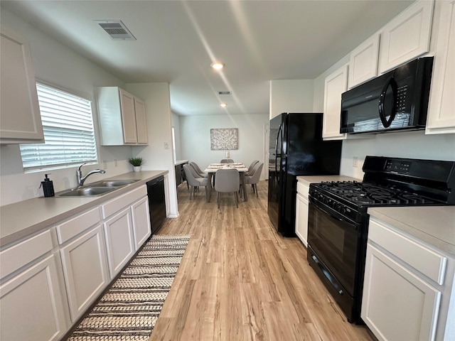 11079 N Lake Mist Ln, Willis, TX 77318 - kitchen with black appliances, light wood-style flooring, white cabinetry, and light countertops