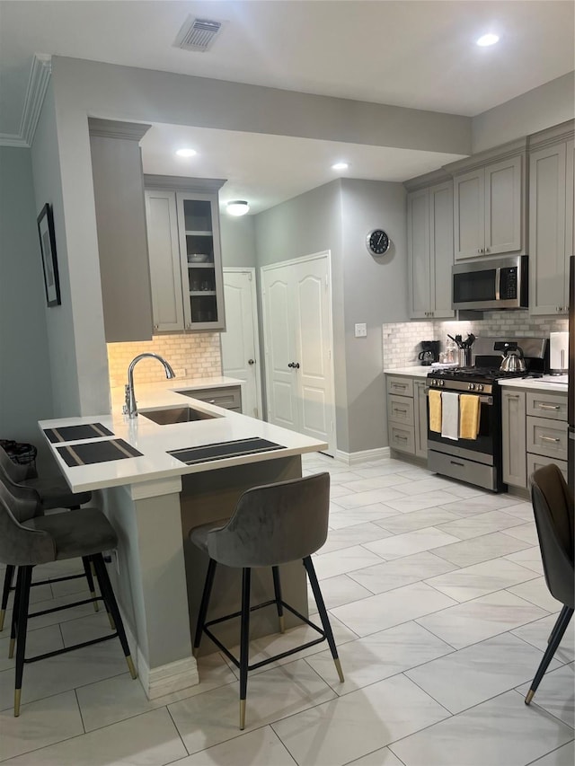 5339 Canyon Hollow Dr, Houston, TX 77084 - kitchen featuring stainless steel appliances, a sink, gray cabinets, a breakfast bar area, and backsplash