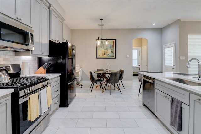 5339 Canyon Hollow Dr, Houston, TX 77084 - kitchen featuring stainless steel appliances, a sink, arched walkways, light countertops, and backsplash