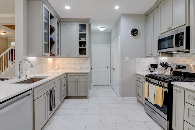 5339 Canyon Hollow Dr, Houston, TX 77084 - kitchen featuring appliances with stainless steel finishes, a sink, gray cabinetry, backsplash, and crown molding