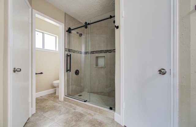18011 Glenledi Dr, Houston, TX 77084 - full bathroom with a stall shower, toilet, a textured ceiling, tile patterned flooring, and baseboards