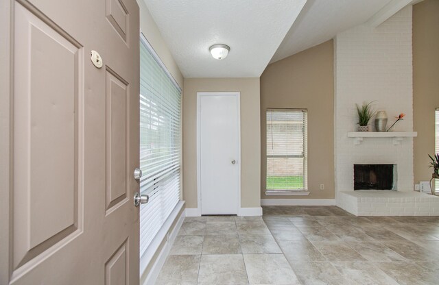 18011 Glenledi Dr, Houston, TX 77084 - foyer entrance featuring a fireplace, vaulted ceiling, baseboards, and light tile patterned flooring