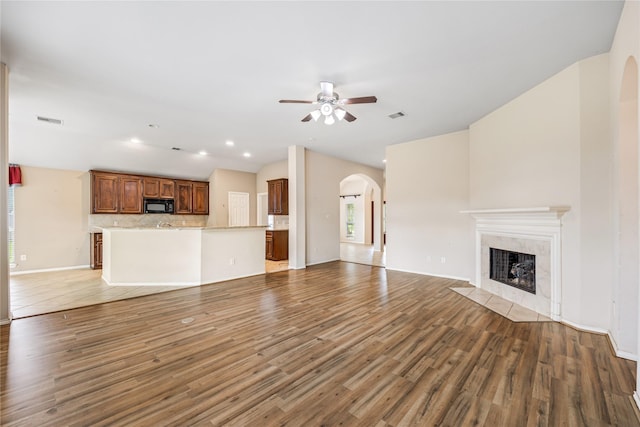 31827 Oak Thicket Ct, Conroe, TX 77385 - unfurnished living room with arched walkways, ceiling fan, light wood-style floors, a premium fireplace, and lofted ceiling