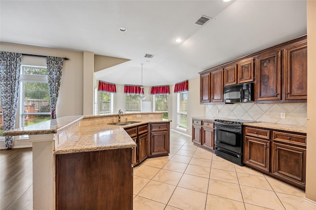 31827 Oak Thicket Ct, Conroe, TX 77385 - kitchen featuring black appliances, decorative backsplash, light stone countertops, pendant lighting, and a large island with sink