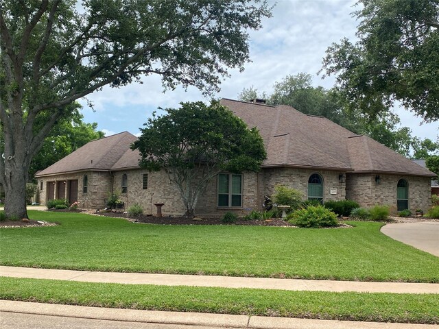 216 Dewberry Dr, Lake Jackson, TX 77566 - view of front of property featuring a front lawn, a garage, a shingled roof, and brick siding