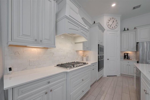 10615 Winding Arbor Ct, Cypress, TX 77433 - kitchen with stainless steel appliances, white cabinetry, backsplash, light countertops, and ornamental molding