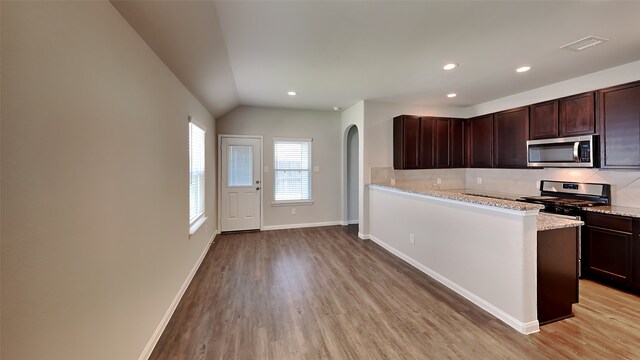 24734 Signorelli Way, Katy, TX 77493 - kitchen featuring stainless steel appliances, arched walkways, light wood-type flooring, backsplash, and vaulted ceiling