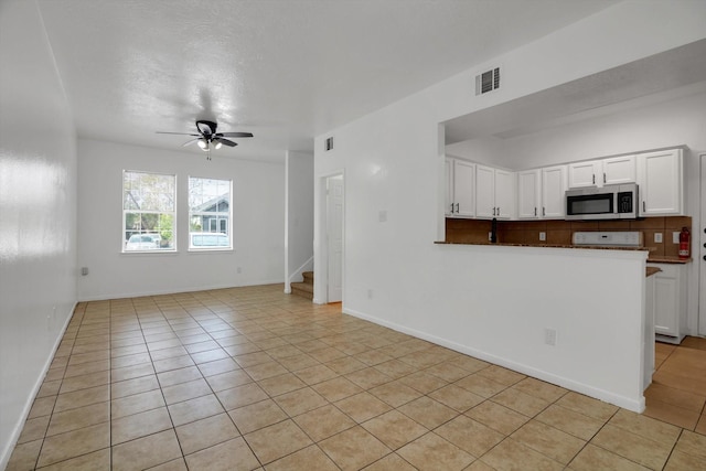 6933 Liverpool St, Houston, TX 77021 - unfurnished living room with light tile patterned flooring, ceiling fan, stairs, and baseboards