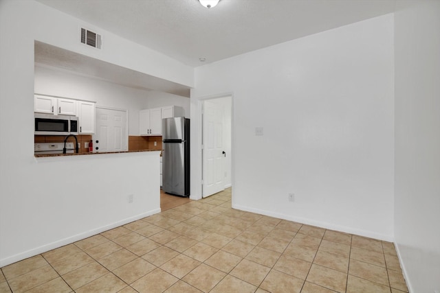 6933 Liverpool St, Houston, TX 77021 - kitchen with appliances with stainless steel finishes, white cabinets, baseboards, dark countertops, and light tile patterned floors