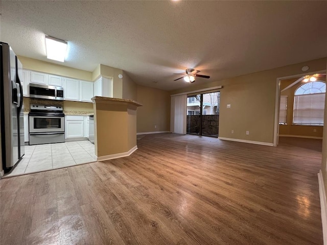 2300 Old Spanish Trl Unit 1111, Houston, TX 77054 - kitchen with appliances with stainless steel finishes, a ceiling fan, light wood finished floors, white cabinets, and open floor plan