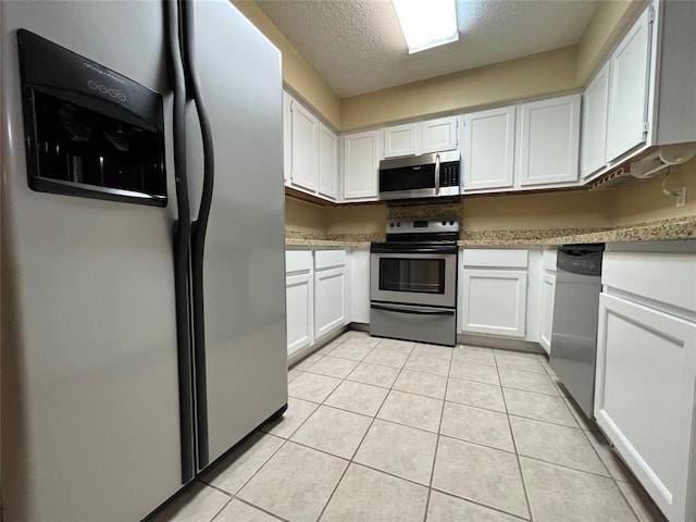 2300 Old Spanish Trl Unit 1111, Houston, TX 77054 - kitchen featuring stainless steel appliances, white cabinets, light tile patterned floors, and a textured ceiling