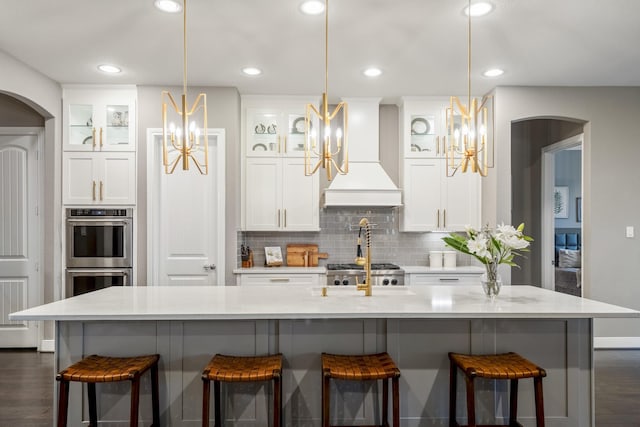 28203 Middlewater View Ln, Katy, TX 77494 - kitchen with premium range hood, a chandelier, arched walkways, double oven, and recessed lighting