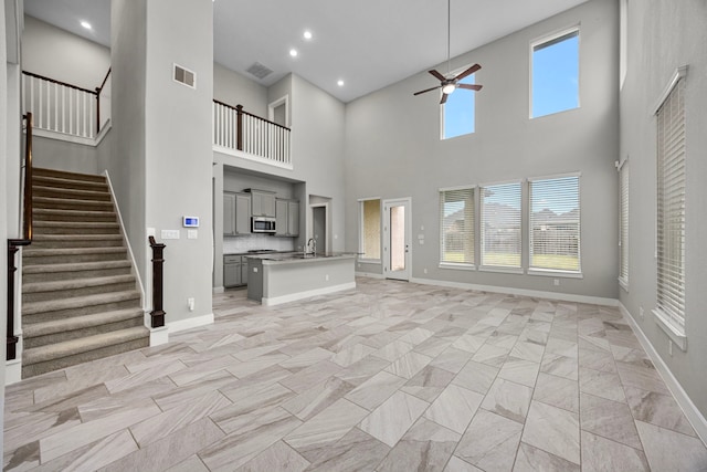 13207 Terania Cliff Trce, Houston, TX 77059 - unfurnished living room with ceiling fan, baseboards, a high ceiling, stairway, and light marble finish floors