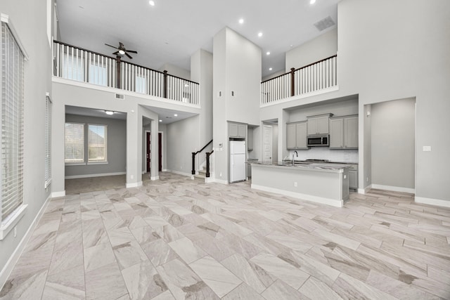 13207 Terania Cliff Trce, Houston, TX 77059 - kitchen featuring stainless steel microwave, gray cabinetry, freestanding refrigerator, open floor plan, and a high ceiling