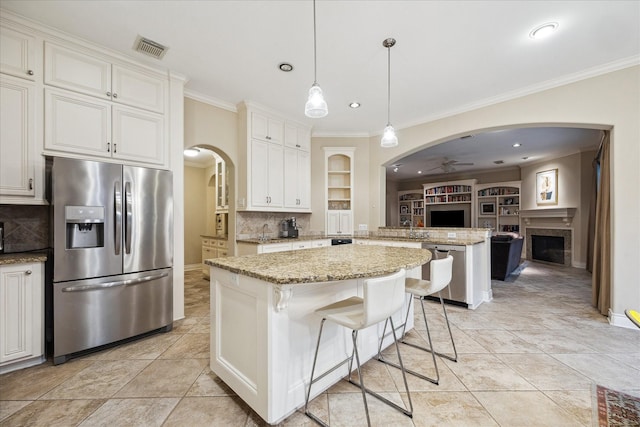 4436 Holt St, Bellaire, TX 77401 - kitchen with stainless steel appliances, a fireplace, a peninsula, arched walkways, and ornamental molding