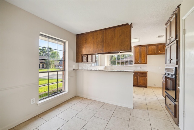 2302 Bright Meadows Dr, Missouri City, TX 77489 - kitchen featuring black oven, a peninsula, tasteful backsplash, and light tile patterned flooring