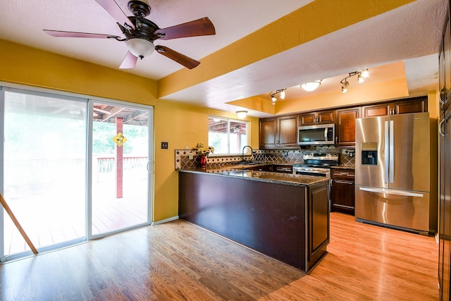 23423 Earlmist Dr, Spring, TX 77373 - kitchen with stainless steel appliances, a peninsula, light wood-style flooring, and backsplash